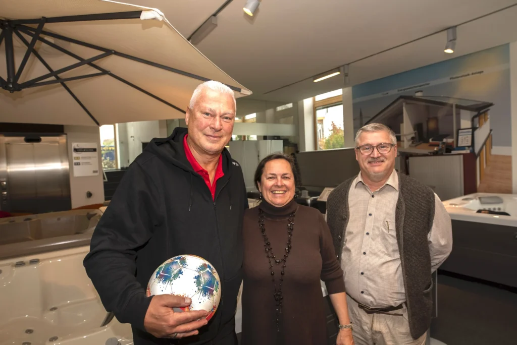 Review HotSpring Hausmessen! 6 Besucherinnen und Besucher bei einer HotSpring Hausmesse im Showroom, umgeben von Whirlpools und Wellness-Produkten, in freundlicher Event-Atmosphäre – HotSpring
